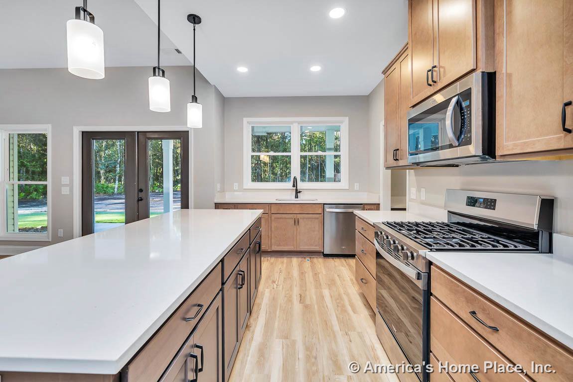 Light wood cabinetry and quartz countertops with stainless steel appliances, large kitchen island, pendant lighting, double window above sink, French doors to exterior, built-in