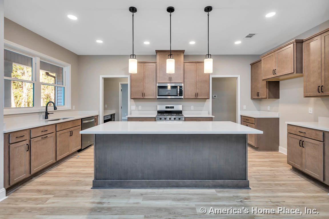 Spacious kitchen with large quartz island, wood shaker cabinets, stainless steel appliances, wide plank flooring, pendant lights above island, recessed ceiling lighting, and double