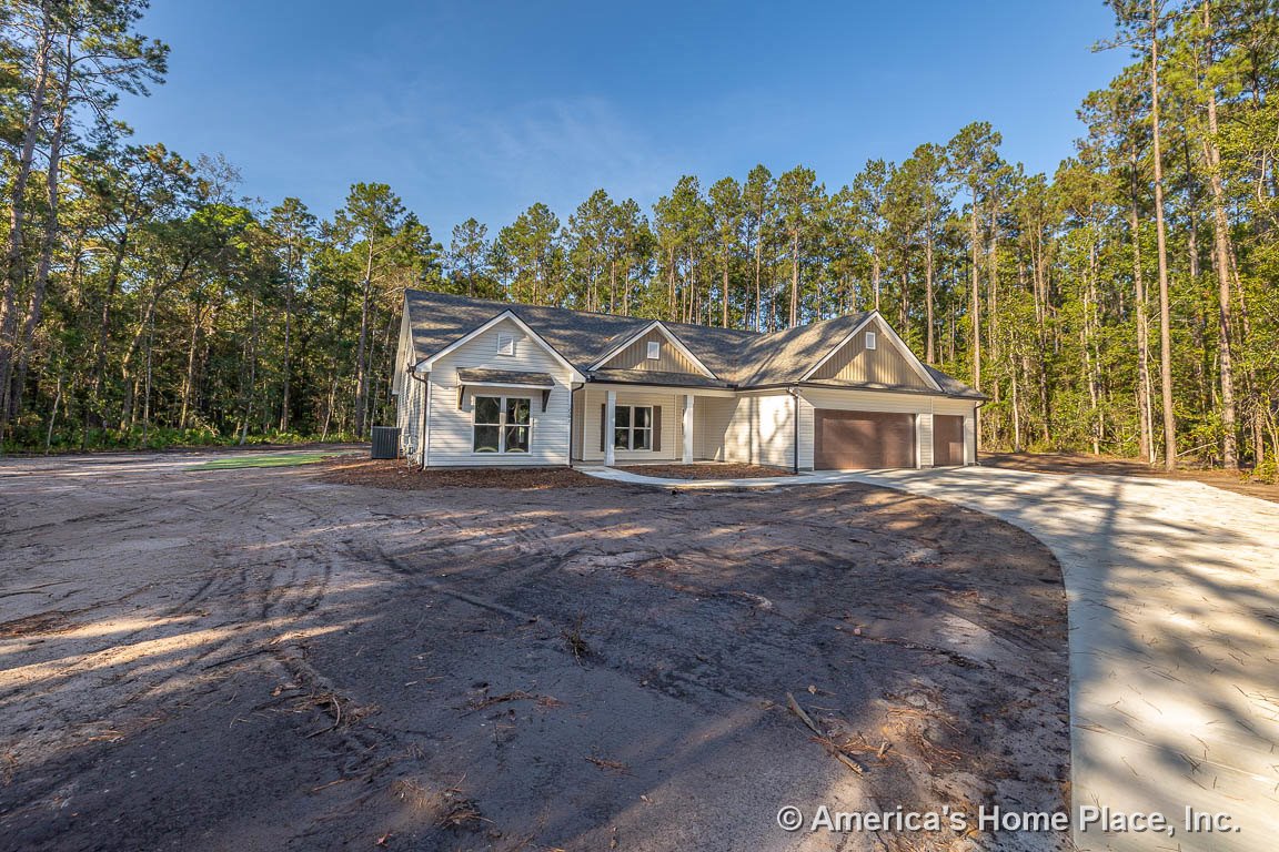 Covered front porch with gabled roof, large front windows, attached double garage doors, vinyl siding exterior, and concrete driveway.