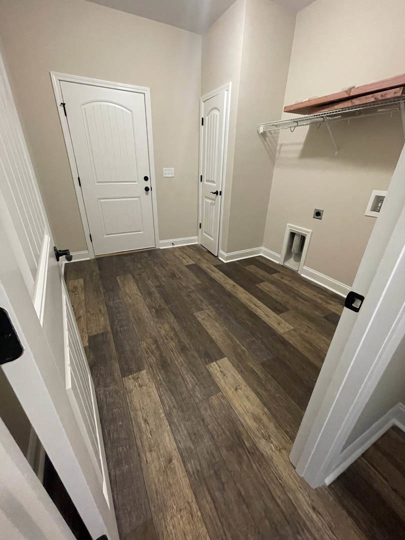 White paneled doors with black handles, hardwood flooring, white walls, and baseboards in a residential interior room