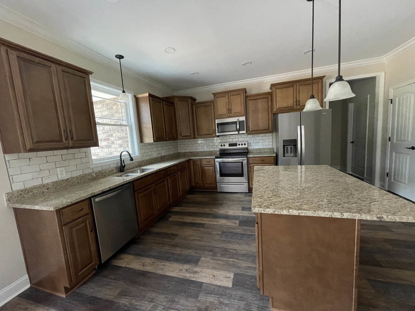 Marble kitchen island with black faucet, stainless steel stove, microwave oven, white cabinetry, and integrated dishwasher