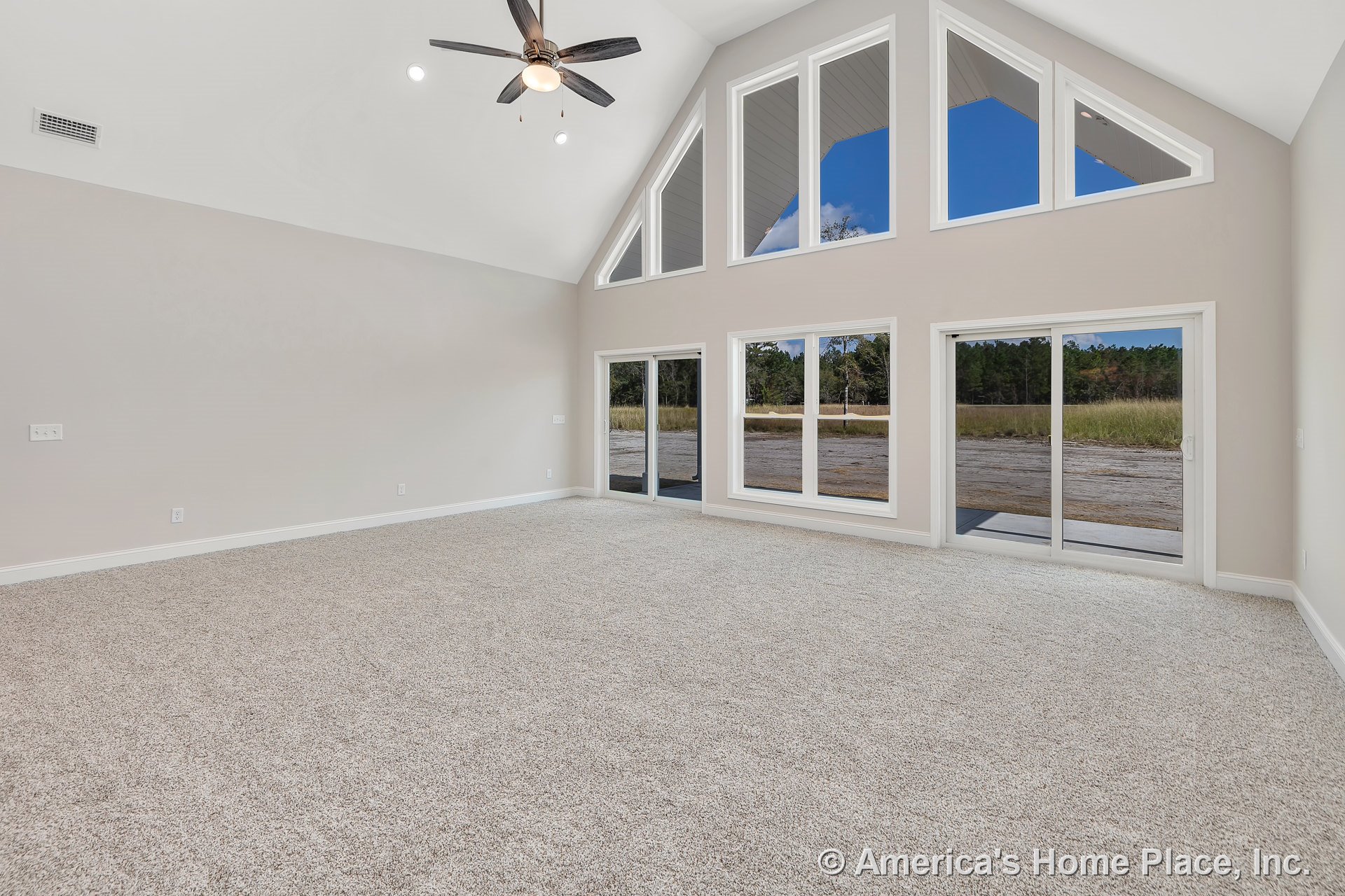 Vaulted ceiling living room with large triangular windows, sliding glass doors, neutral wall paint, recessed lighting, carpet flooring, ceiling fan, baseboard trim, and abundant