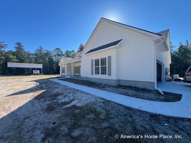 Single-story home with white horizontal siding, gable rooflines, covered front porch, concrete walkway, multiple windows accented by shutters, and attached garage.