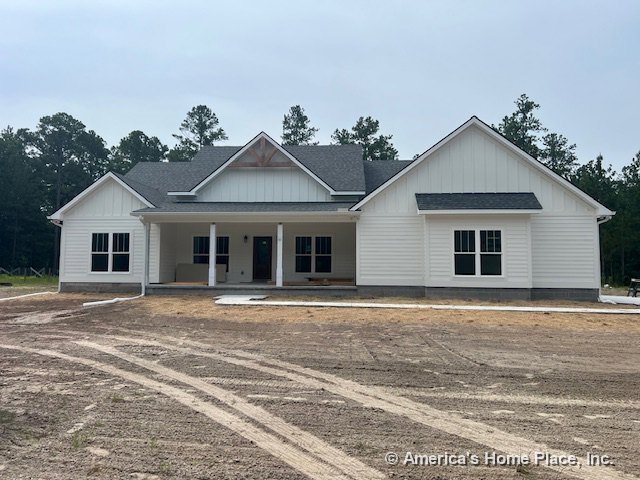 White board and batten siding with multiple gabled rooflines, covered front porch, dark shingle roof, double-hung windows, and trimmed front entry door.
