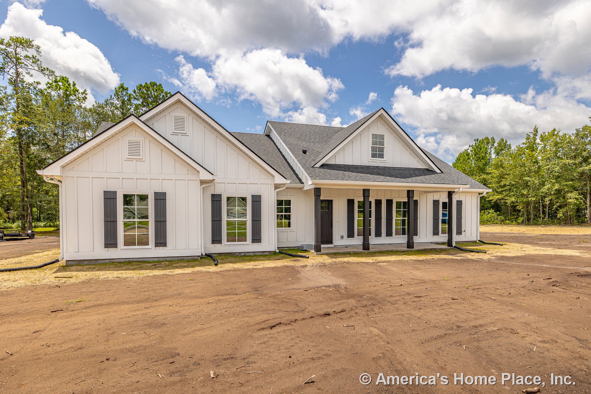 White board and batten siding with dark window shutters, covered front porch supported by columns, multiple front windows, gable roof, and prominent front entry door.