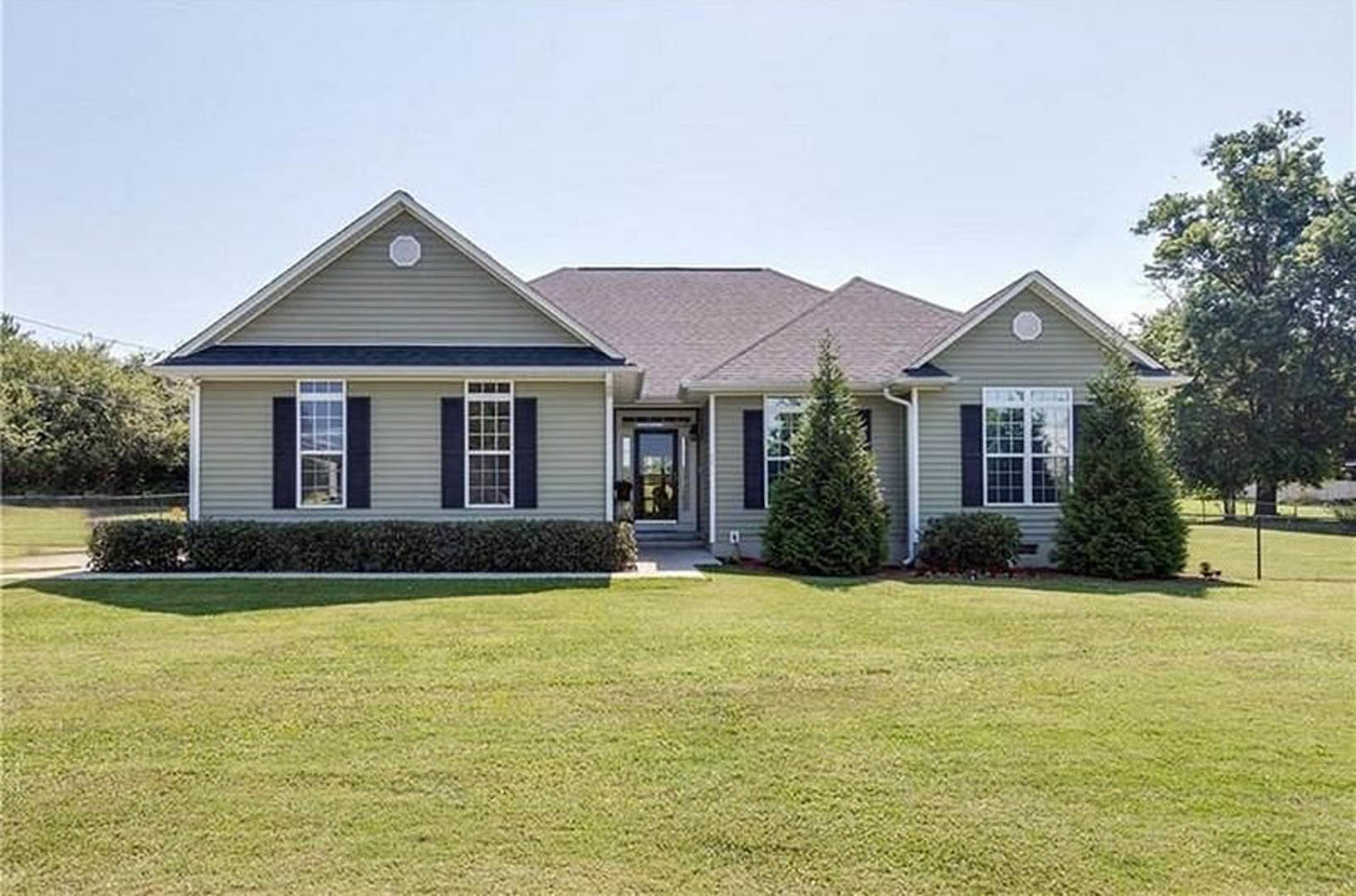 Two-story house with white-framed windows, front door, covered porch, green lawn, and leafy tree in the yard