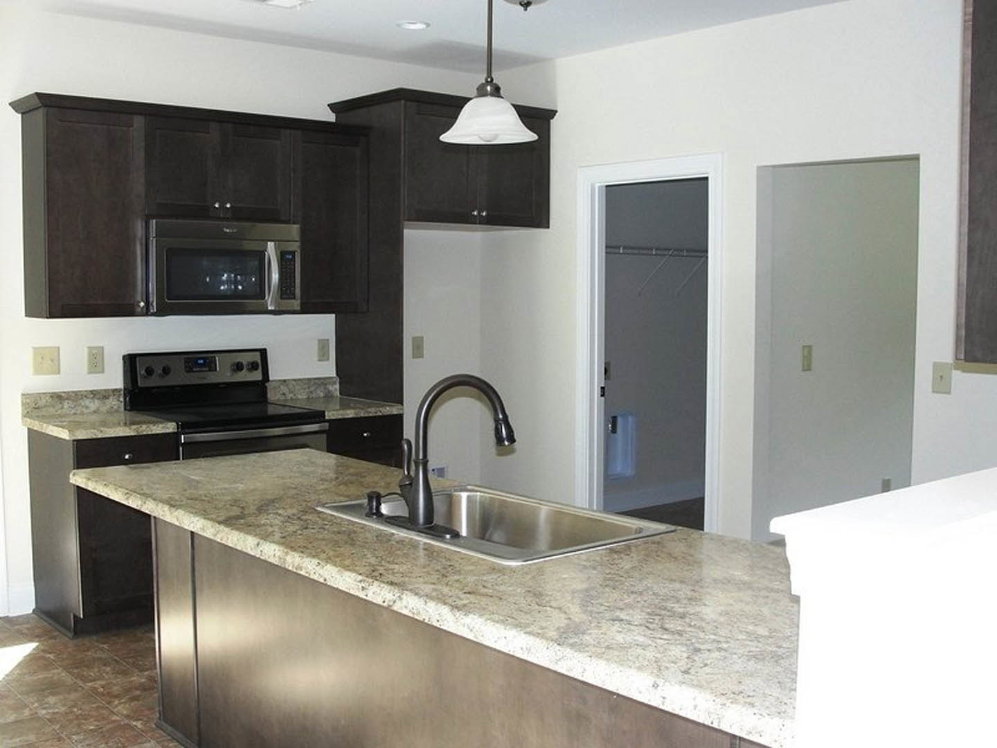 Granite countertops, stainless steel appliances, white cabinetry, built-in microwave, modern sink and faucet, under-cabinet lighting