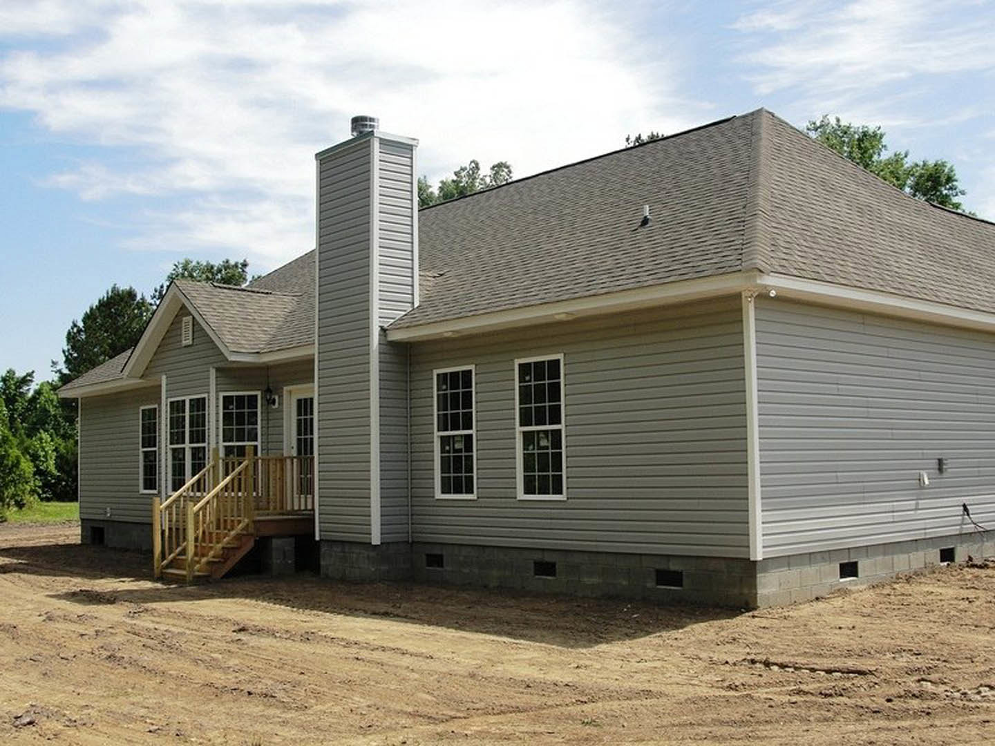 White clapboard house with brick chimney, multi-pane windows, wooden porch and deck, outdoor staircase, leafy tree in foreground, Mark Twain Boyhood Home & Museum visible in