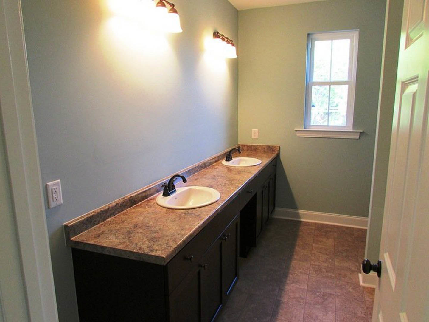 Double vanity bathroom with white sinks, chrome faucets, stone countertop, tile backsplash, white cabinetry, and window with white trim.