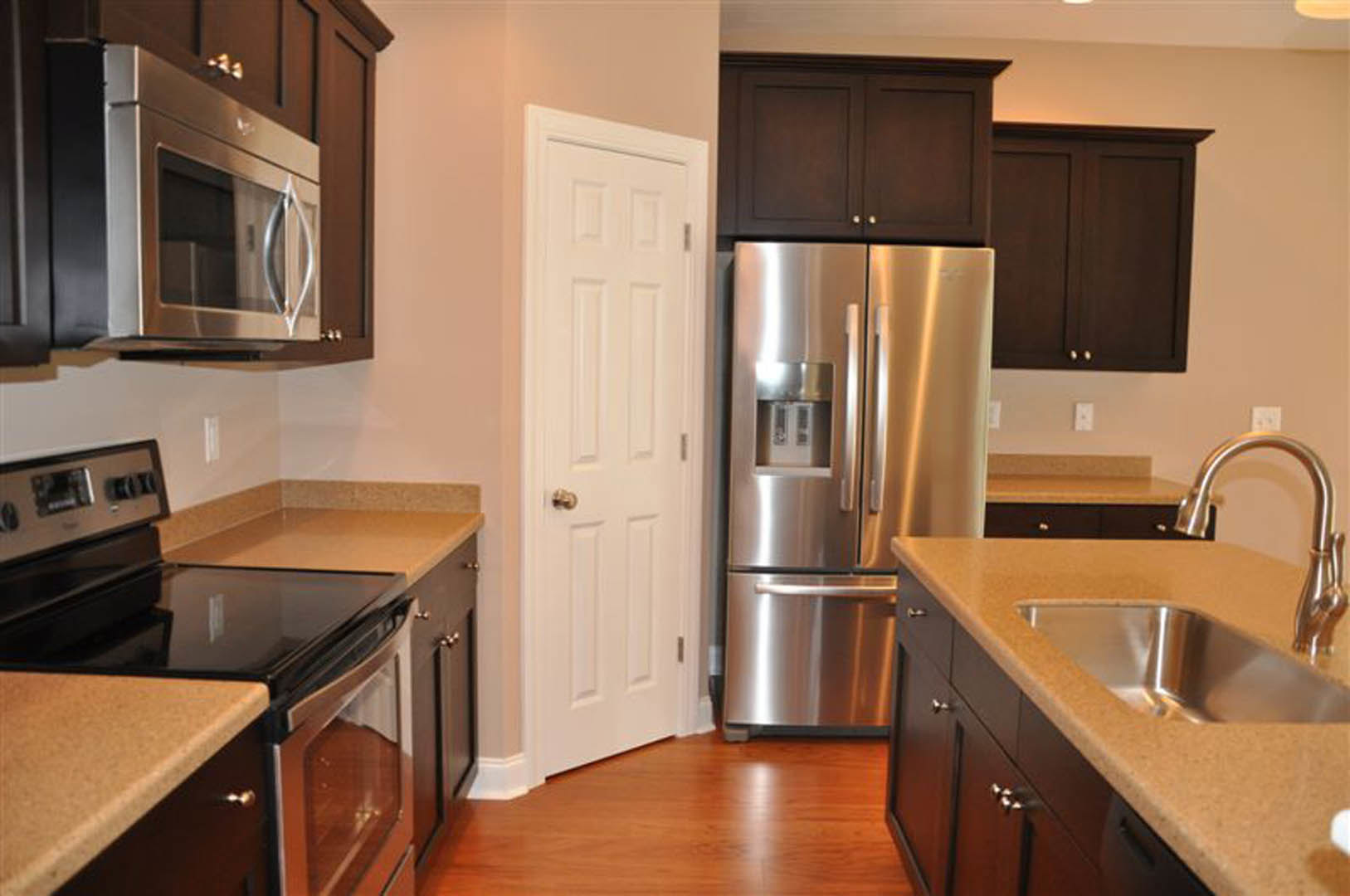 Modern kitchen featuring stainless steel refrigerator, stove, and microwave, white cabinetry, light countertops, and a stainless steel sink