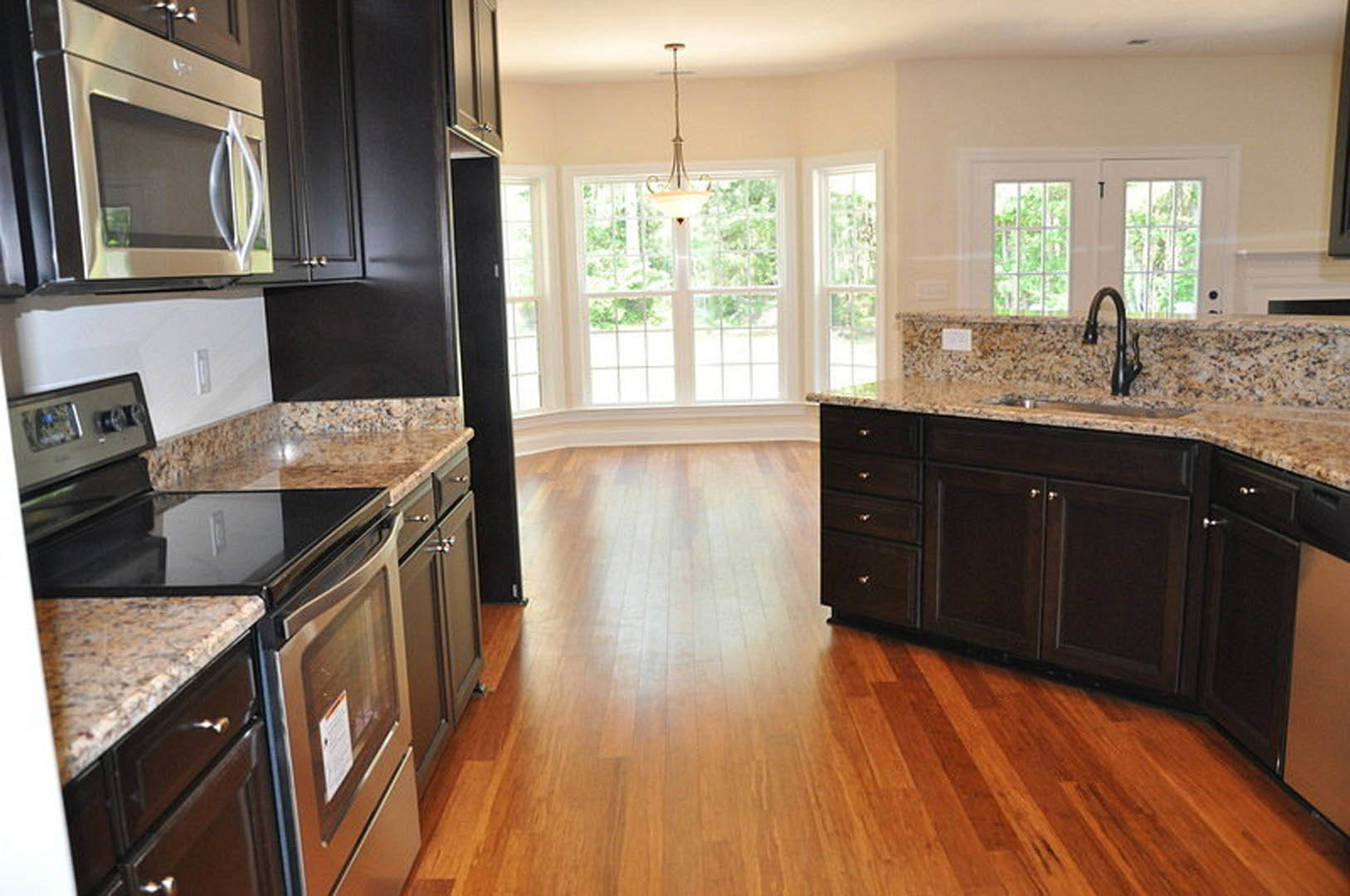 Granite countertops and black cabinets in a modern kitchen, stainless steel microwave, black faucet, and marble-patterned surfaces