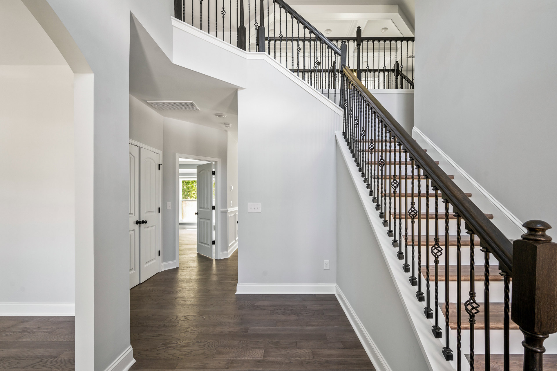 Wood staircase with metal railings, wooden newel post, and adjacent white door in a modern interior