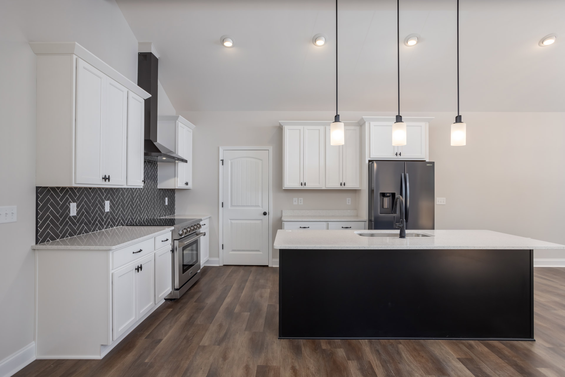 White cabinetry and black island with black countertop and sink, black refrigerator with faucet, stainless steel oven with glass door, white door with black knob, black-based light