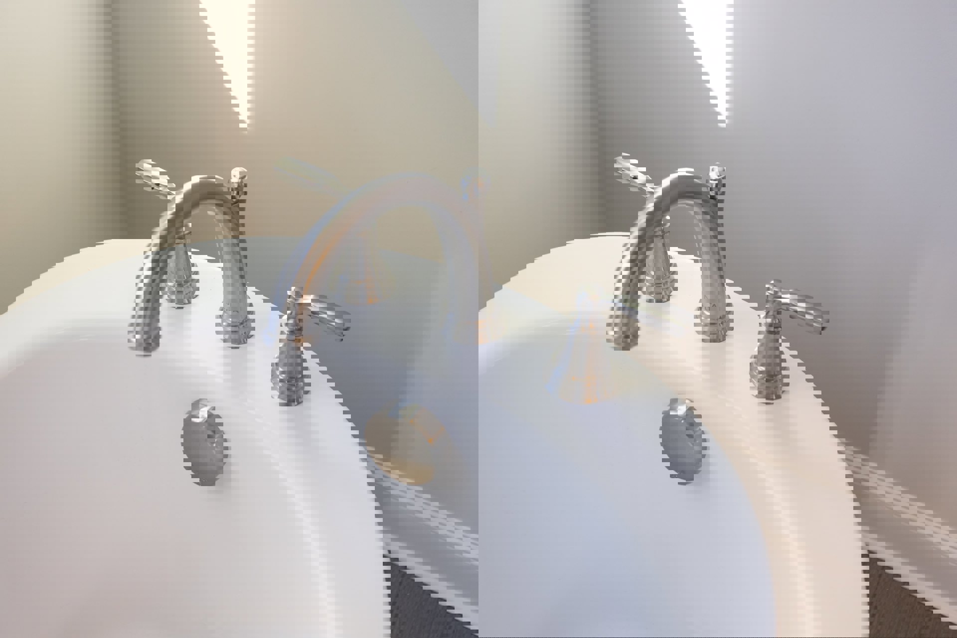 Chrome faucet and rectangular white sink mounted against a smooth white bathroom wall