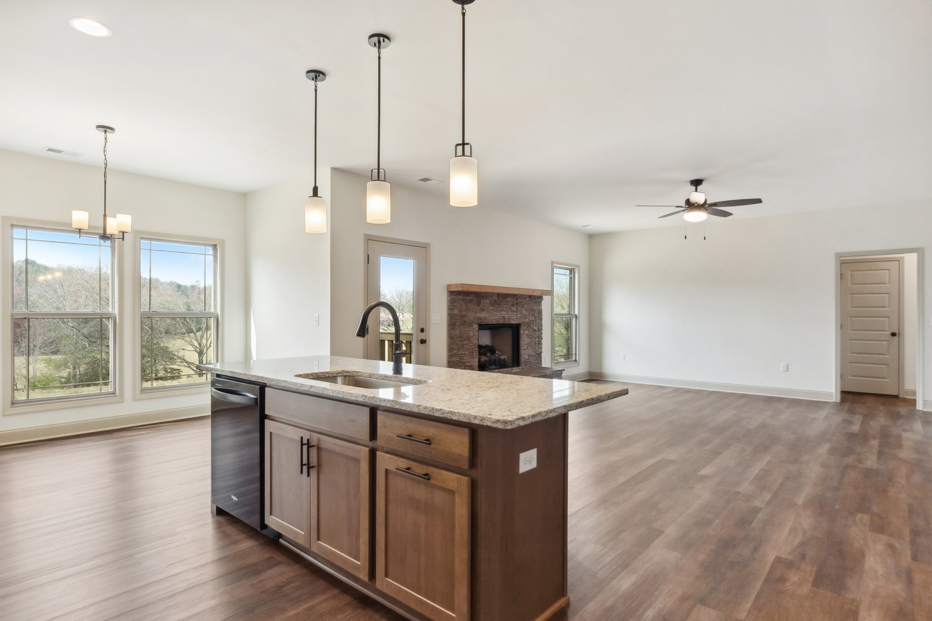 Quartz kitchen island with built-in sink, pendant lighting, tile flooring, white cabinetry, and a white door with black handle