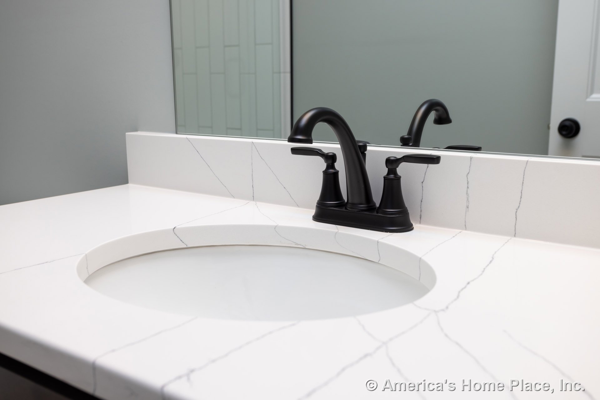 White rectangular sink with black faucet on marble countertop, large wall mirror, light tile backsplash