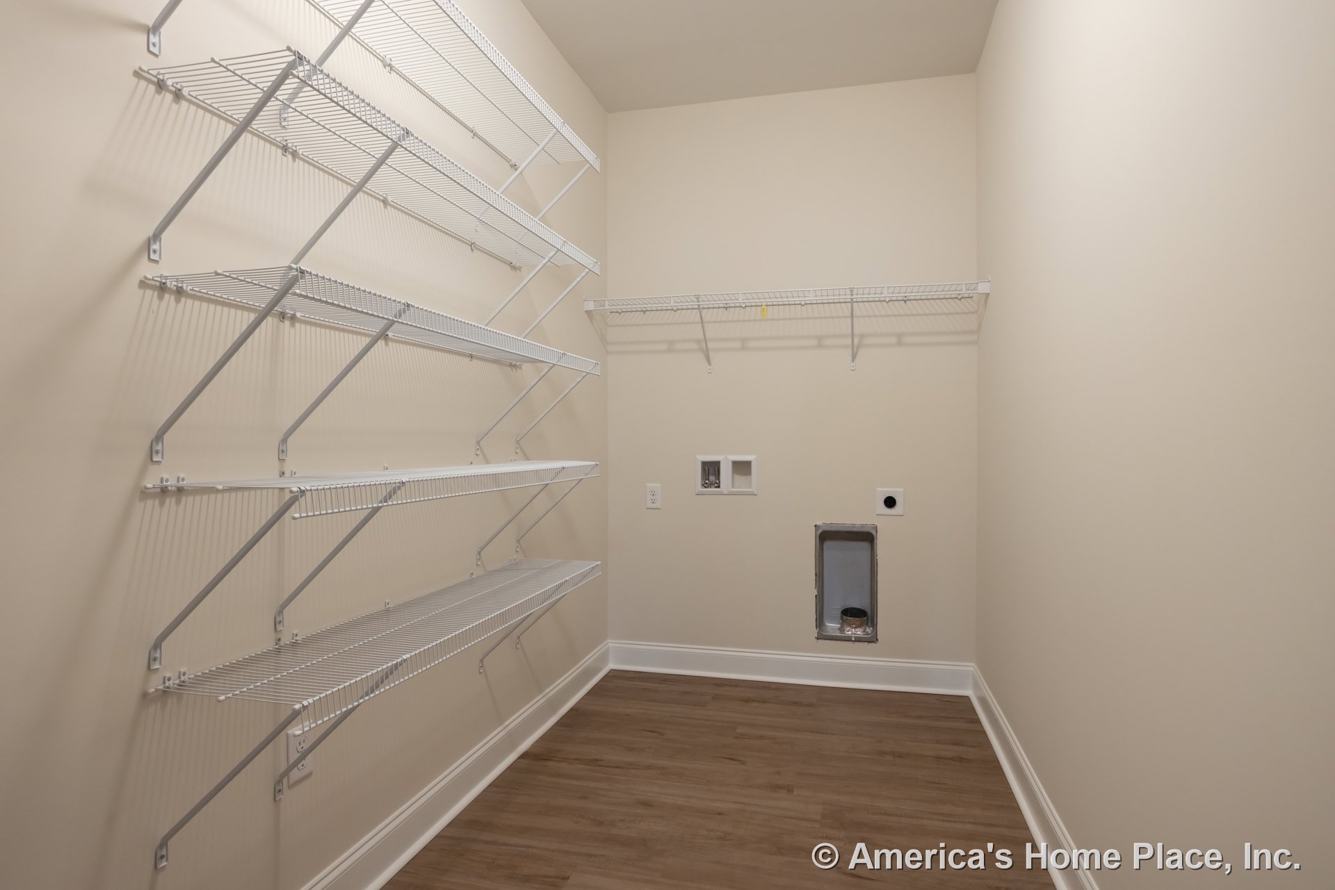White built-in shelves on a plaster wall, wood flooring with white baseboards, exposed metal pipes, and recessed lighting in a modern residential room.