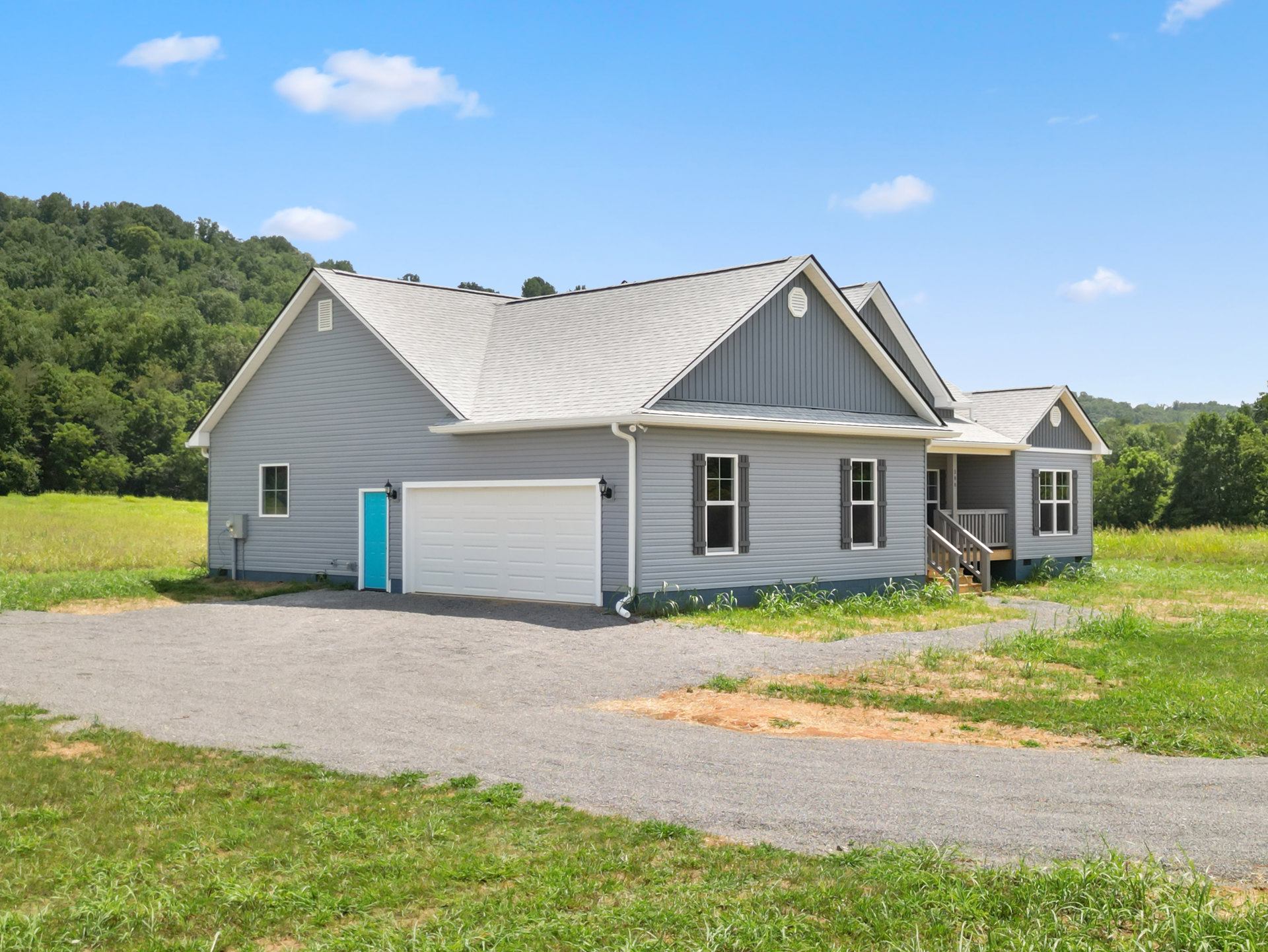Two-story house with gray roof, white garage door, paved driveway, green lawn, and mature trees; Robert Frost Farm visible in the background.