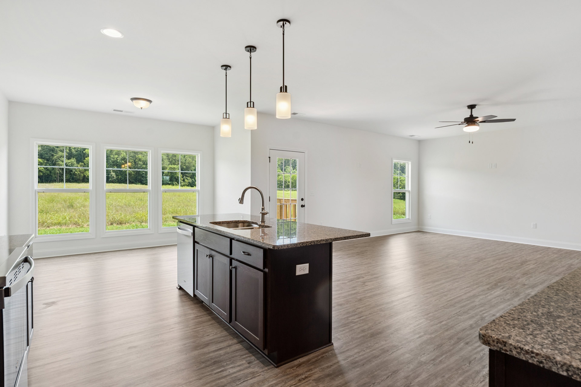 Quartz kitchen island with built-in sink, wood flooring, white cabinetry, wall sconce, and ceiling fan with light fixture