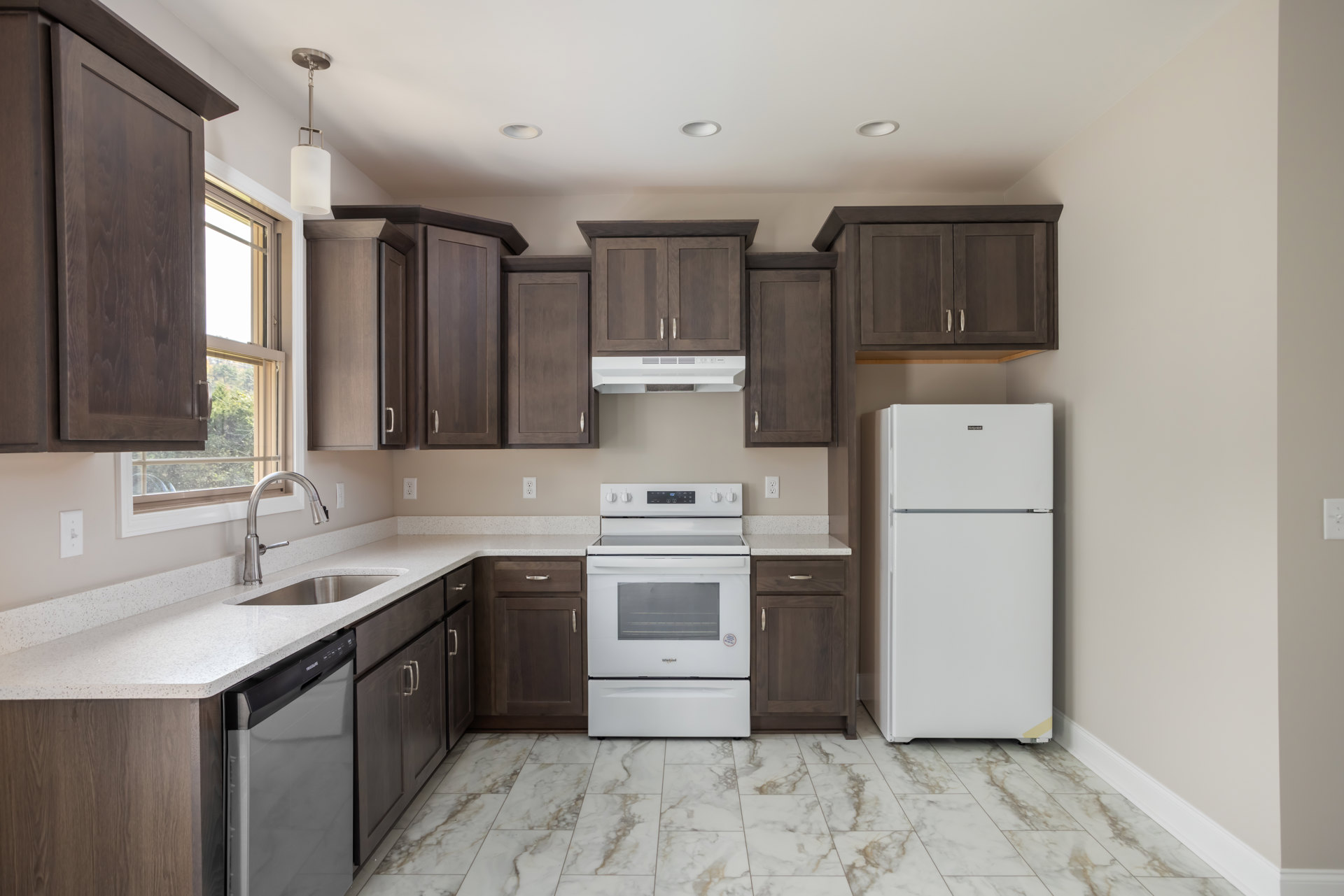 Kitchen with dark wood cabinets, granite countertops, white refrigerator and oven, stainless steel sink, and light fixture above island