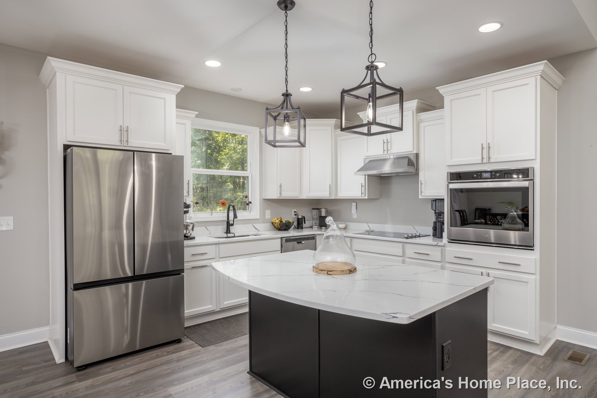 White kitchen cabinets, large central island with quartz countertop, stainless steel double-door refrigerator, glass vase and clear container on island, stainless steel oven with