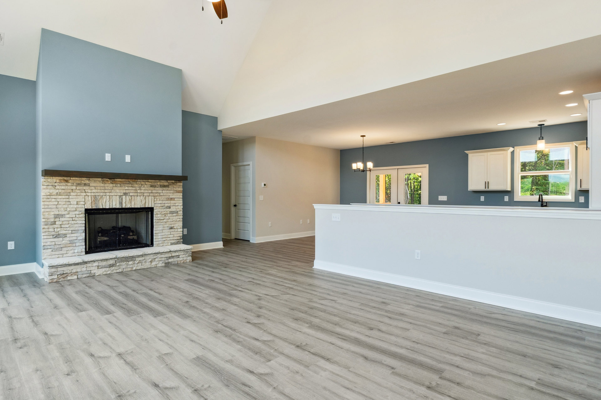 Spacious living room featuring a wood floor, white walls, and a central fireplace with a black mesh screen and glass door