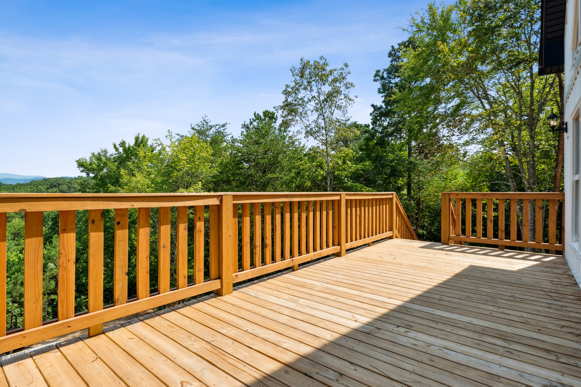 Wooden deck with matching railing overlooking a group of trees, outdoor setting with natural wood finishes