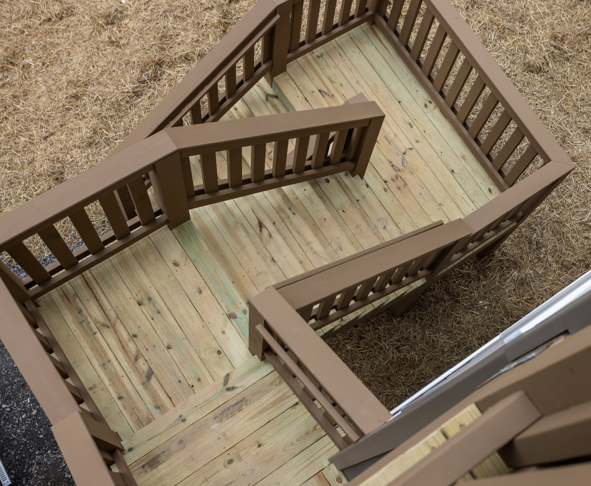 Wooden deck with horizontal railings and stairs, natural wood finish, outdoor ground level