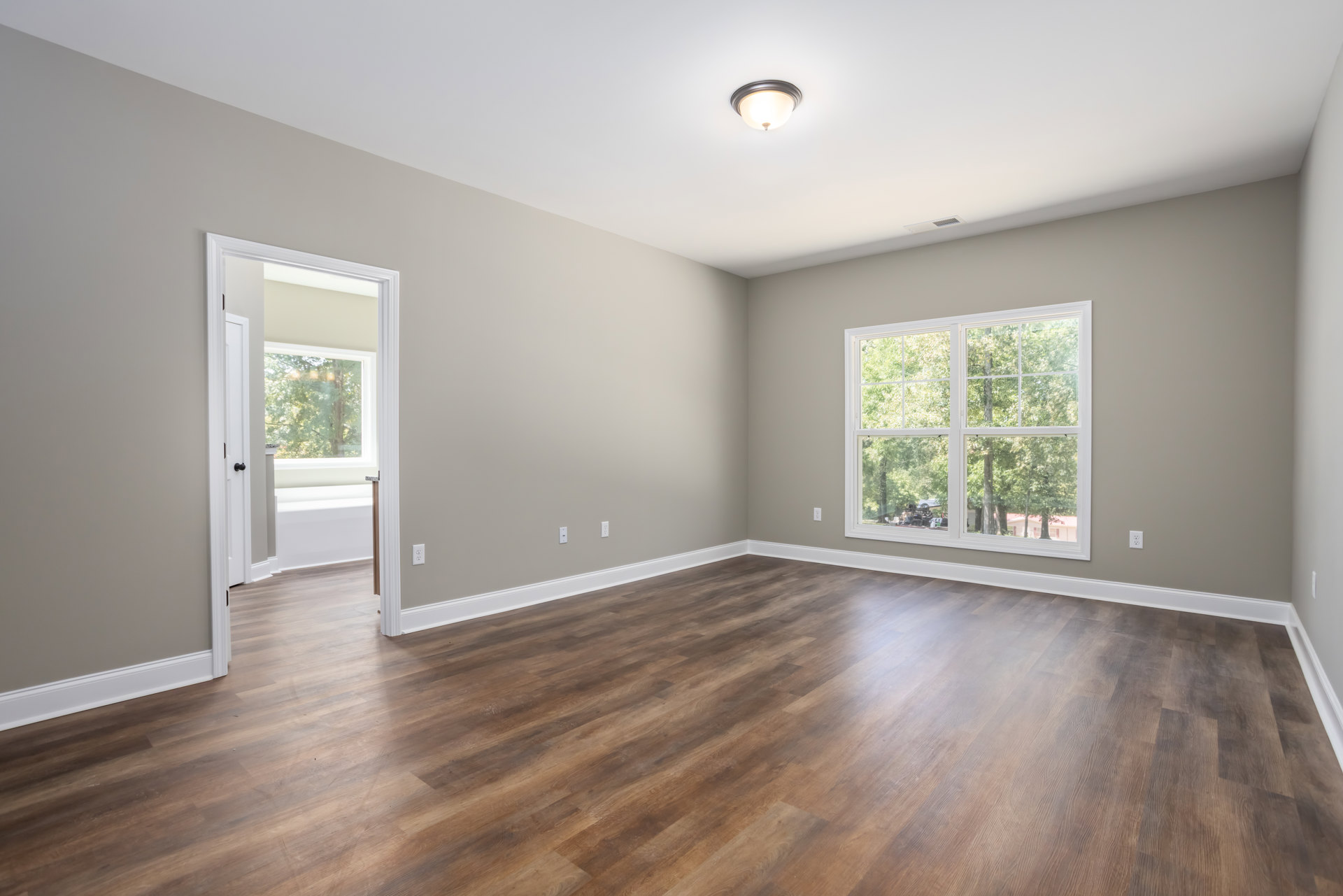 Wood flooring in a room with white walls and large windows overlooking trees