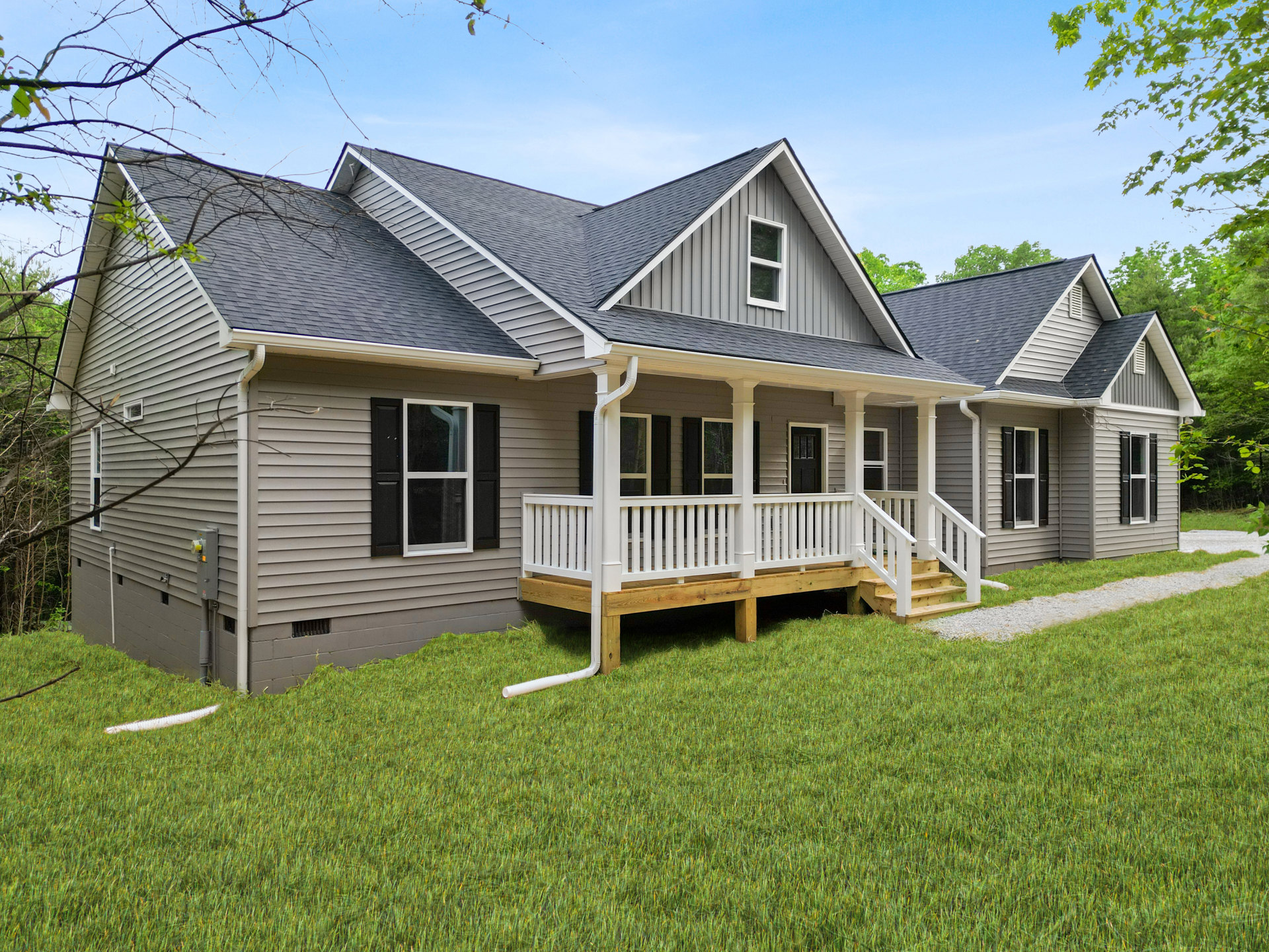 Two-story house with covered porch, white railings, black shuttered windows, and green lawn; Robert Frost Farm visible in the background.