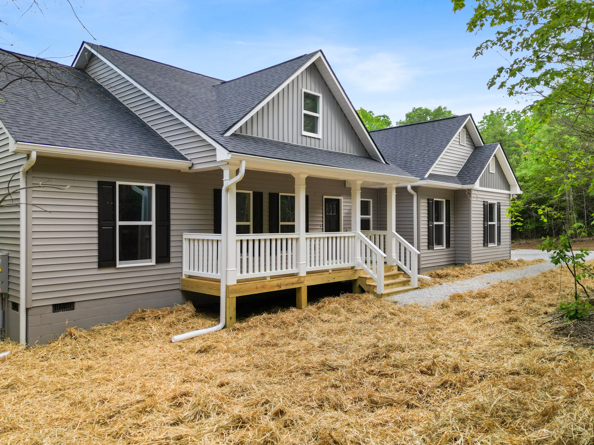 Two-story house with white siding, black shuttered windows, covered porch, white railing deck, and grassy yard; Robert Frost Farm visible in the background.