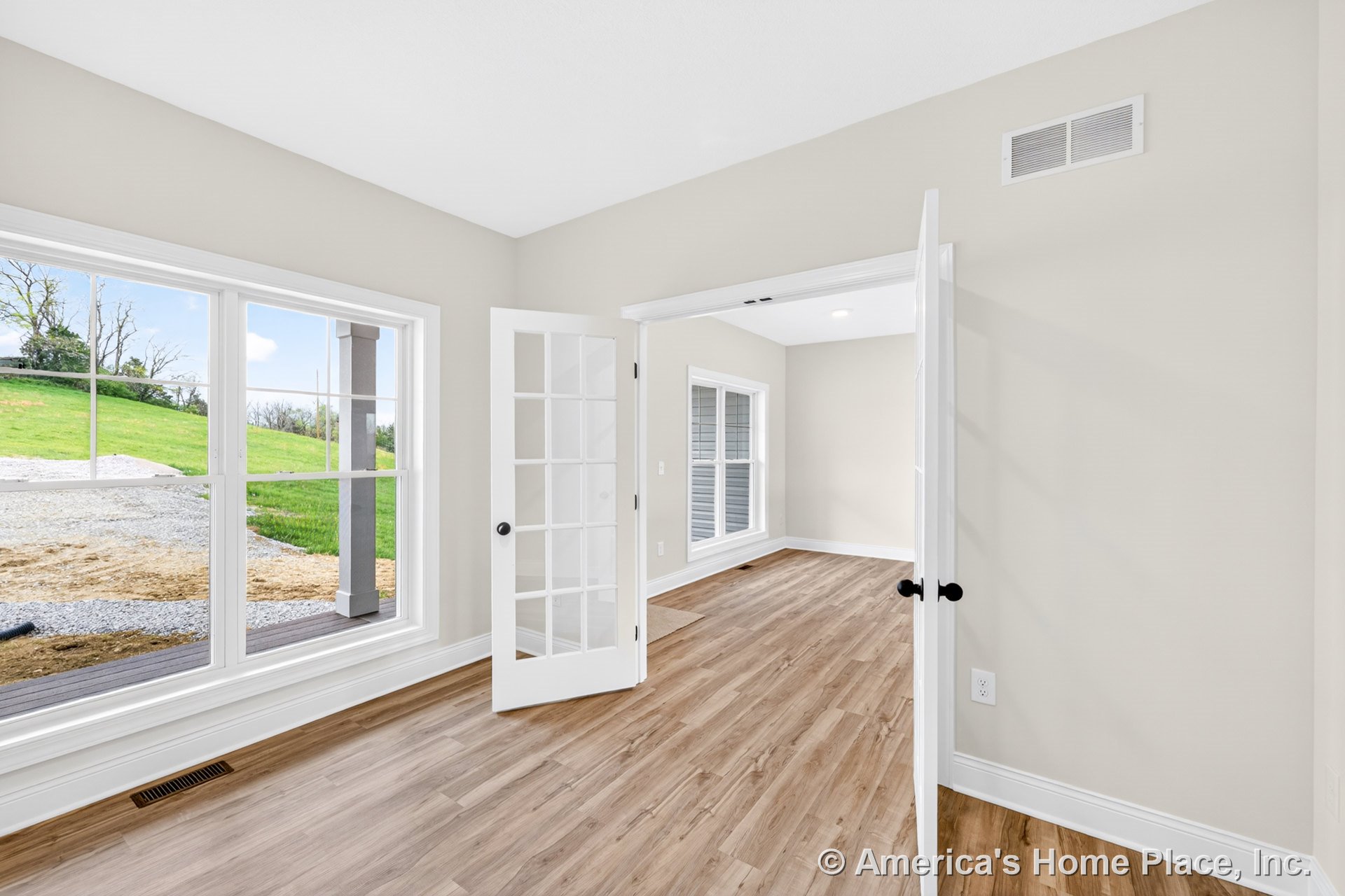 Spacious foyer with large picture windows, white French doors, light wood plank flooring, neutral wall paint, white baseboards, recessed ceiling light, and open layout.