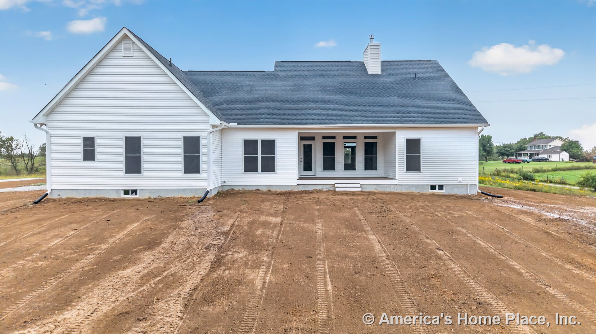 White vinyl siding exterior with multiple rectangular windows, covered rear porch featuring steps, dark shingle roof, and prominent exterior chimney.