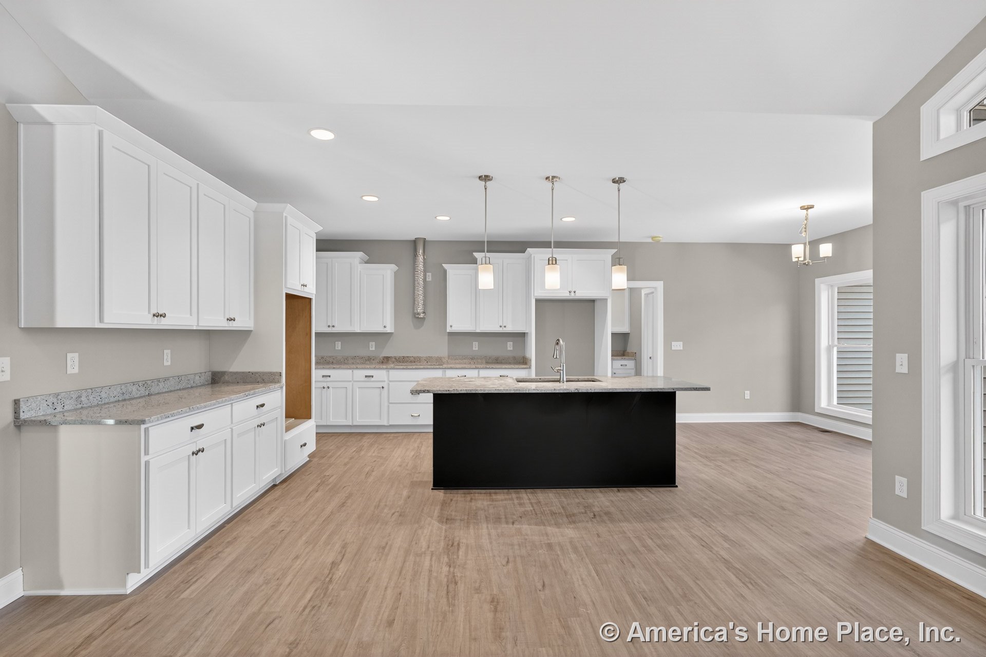 White shaker cabinets and granite countertops line the kitchen, with a black central island beneath pendant lights; wood-look flooring, large trimmed windows, recessed lighting