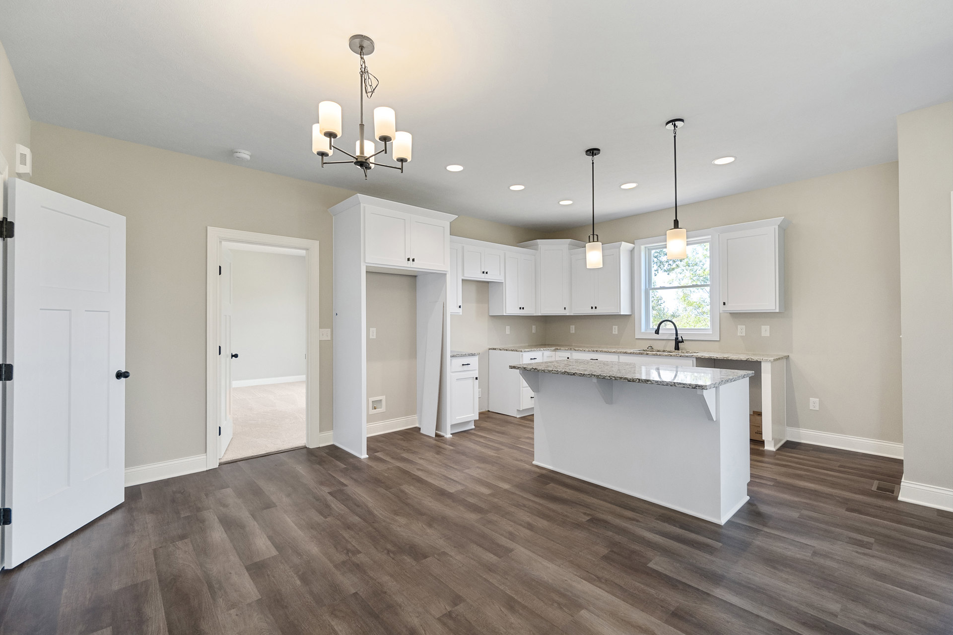 Kitchen with marble countertop bar, wood flooring, white cabinetry, white door with black handle, window with lamp and ceiling light fixture