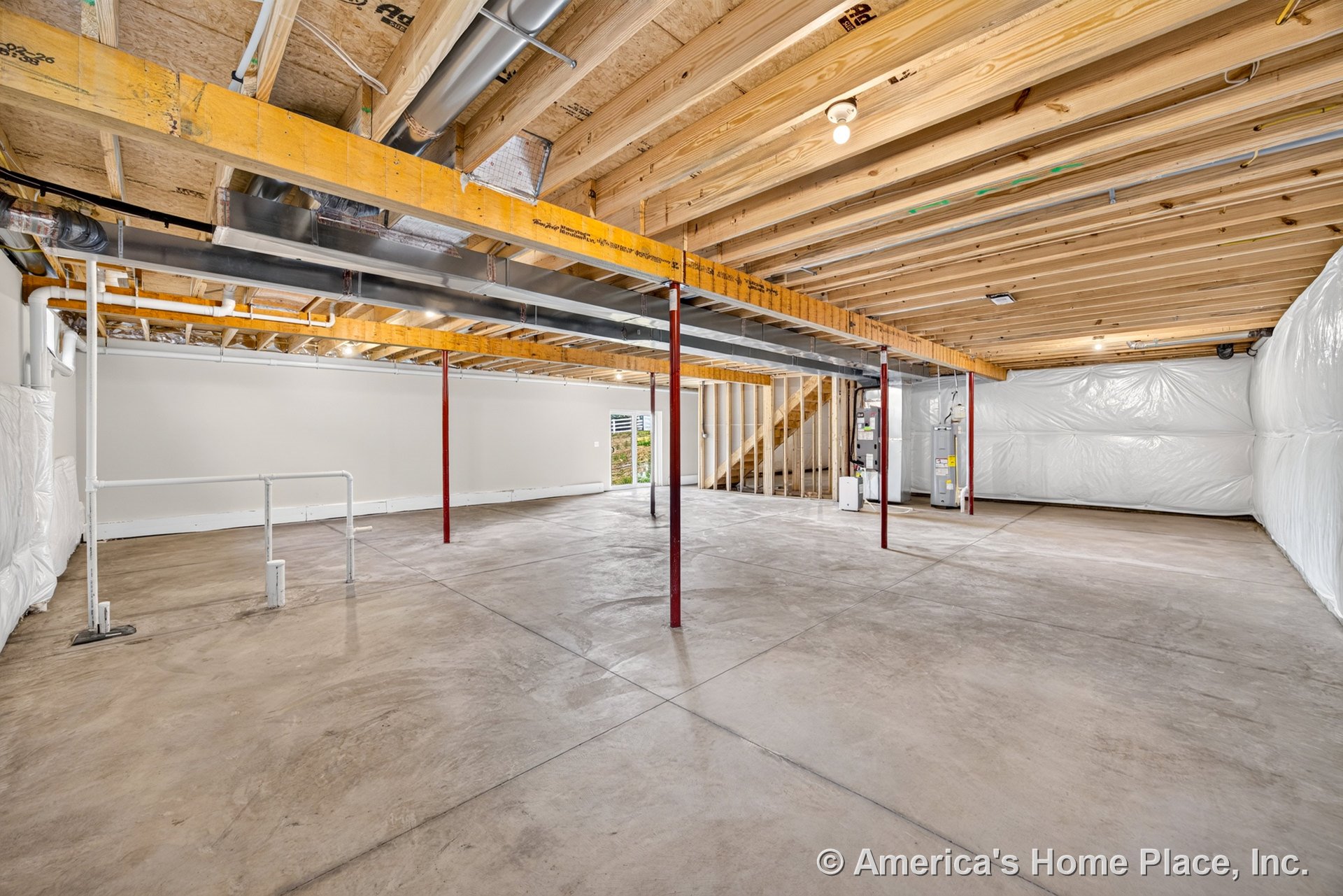 Unfinished basement with exposed wood ceiling joists, concrete slab floor, metal support columns, visible utility pipes and ductwork, insulated walls, wood-framed staircase, and