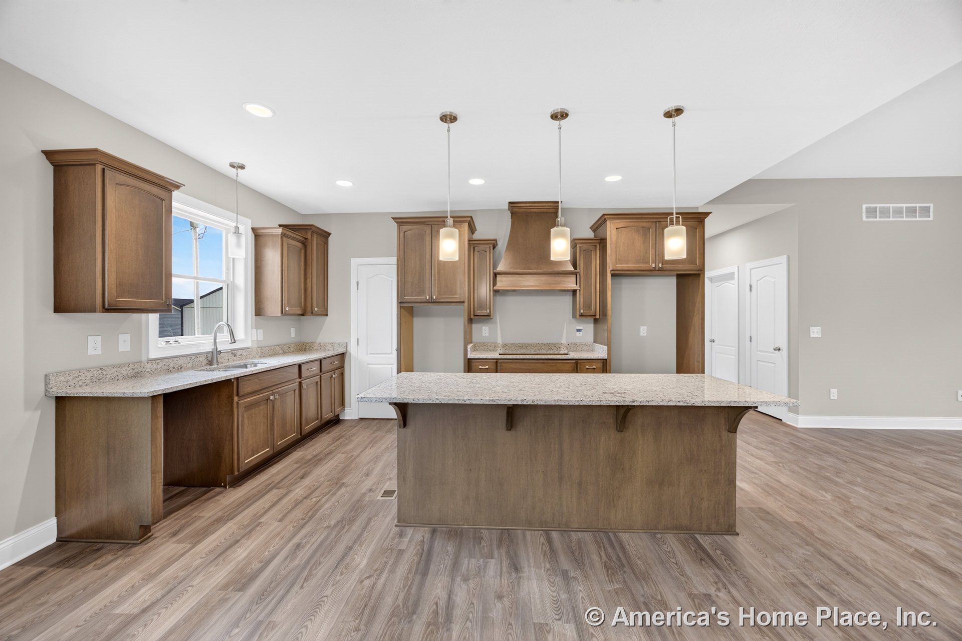 Wood cabinetry kitchen with granite countertops, large central island, pendant and recessed lighting, vinyl plank flooring, built-in hood, window above sink, neutral walls, and