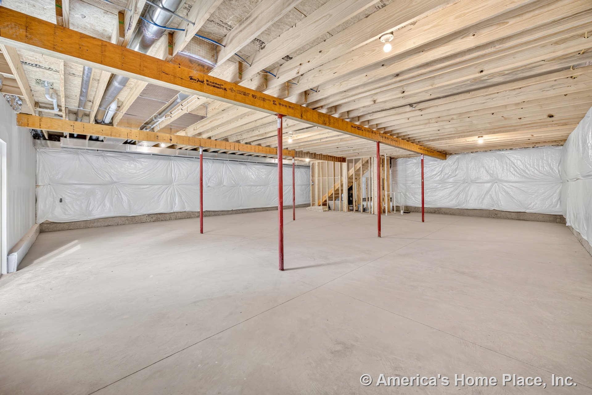 Unfinished basement with exposed wood ceiling joists, concrete floor, plastic-wrapped walls, metal support columns, visible ductwork, unfinished staircase, utility lighting, and