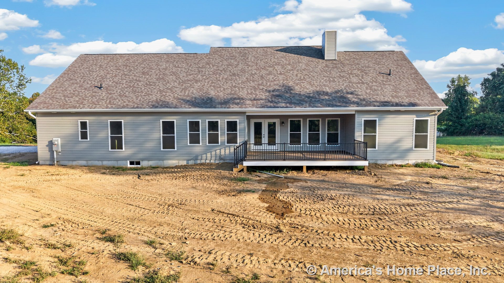 Gray vinyl siding exterior with multiple rectangular windows, covered rear porch featuring black metal railing, asphalt shingle roof, white trim, exterior door, lighting fixture