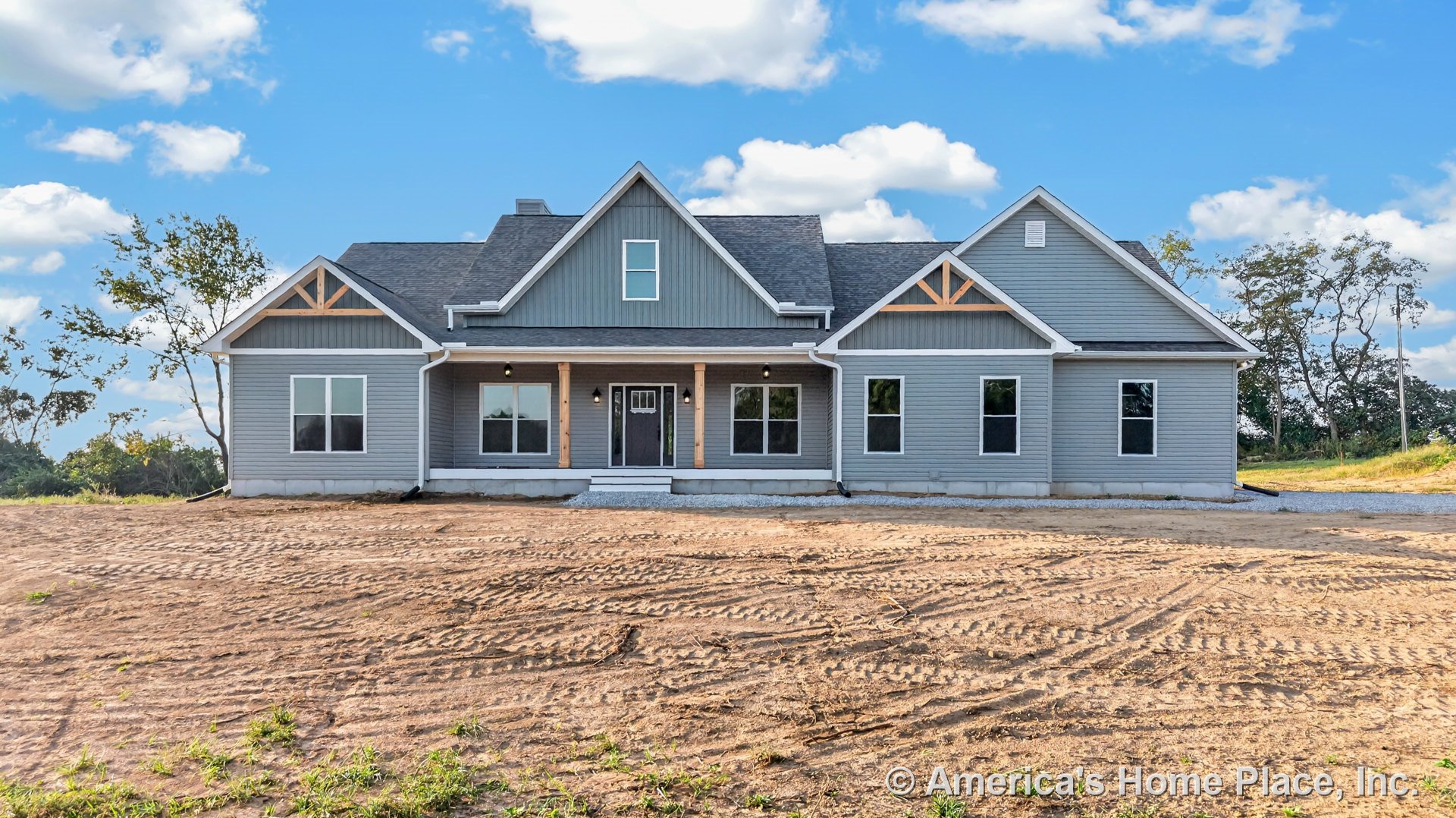 Gray vertical siding and white trim accents on modern farmhouse exterior with multiple gabled rooflines, covered front porch supported by wood columns, large windows, and