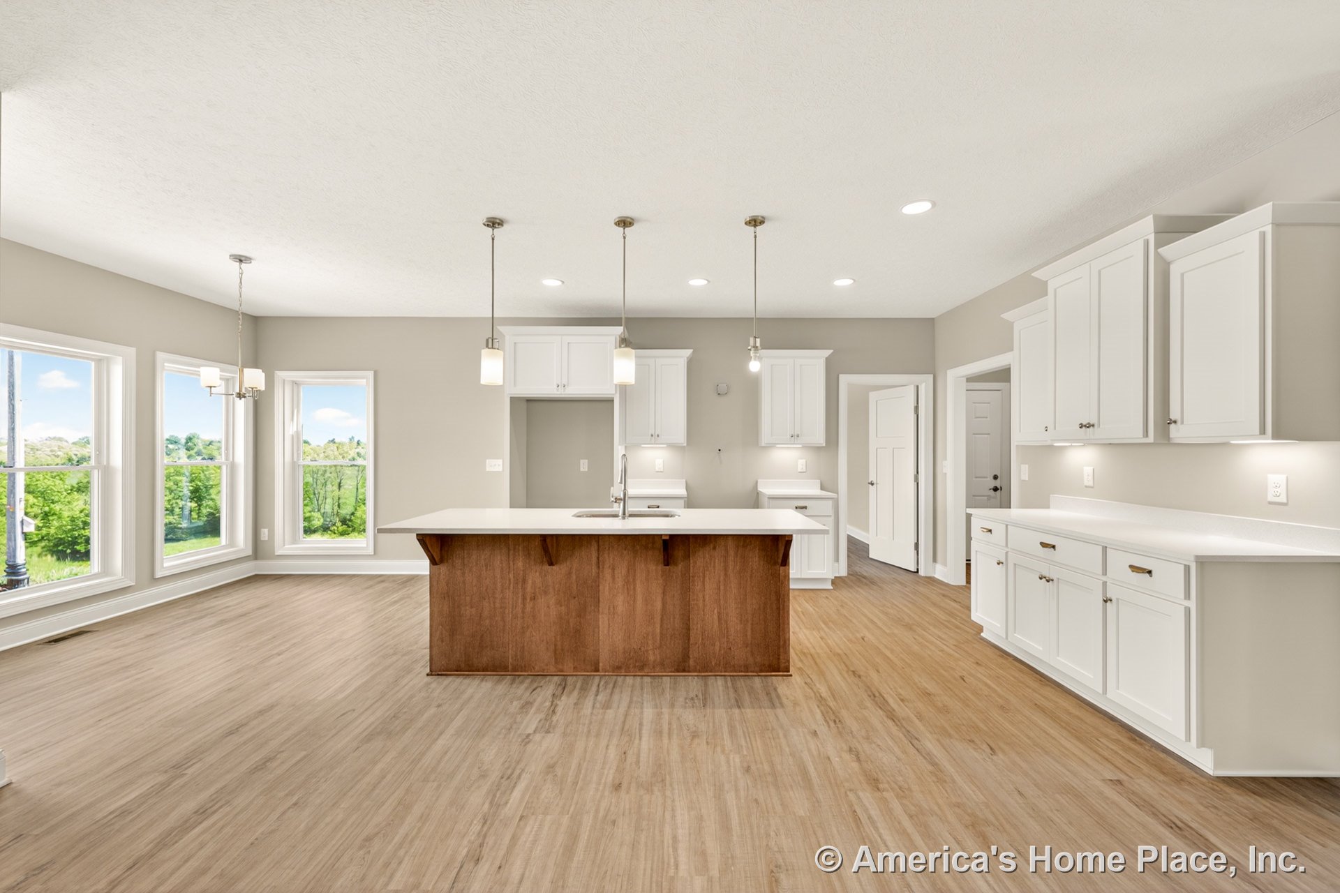 Open kitchen with white shaker cabinets, quartz countertops, wood center island, pendant and recessed lighting, large dining area windows, light wood flooring, and neutral walls.