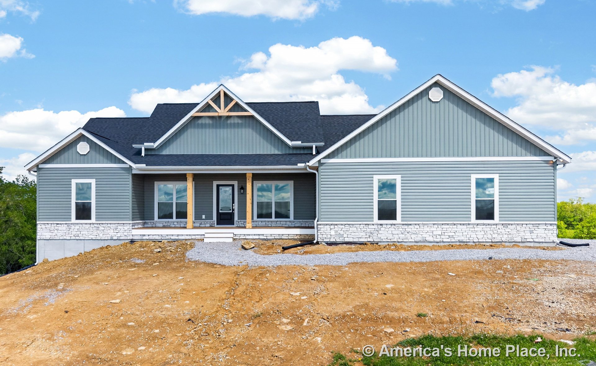 Gray vinyl siding exterior with stone veneer foundation, covered front porch supported by wood columns, black shingle gabled roof, white trim windows, and single front door on new