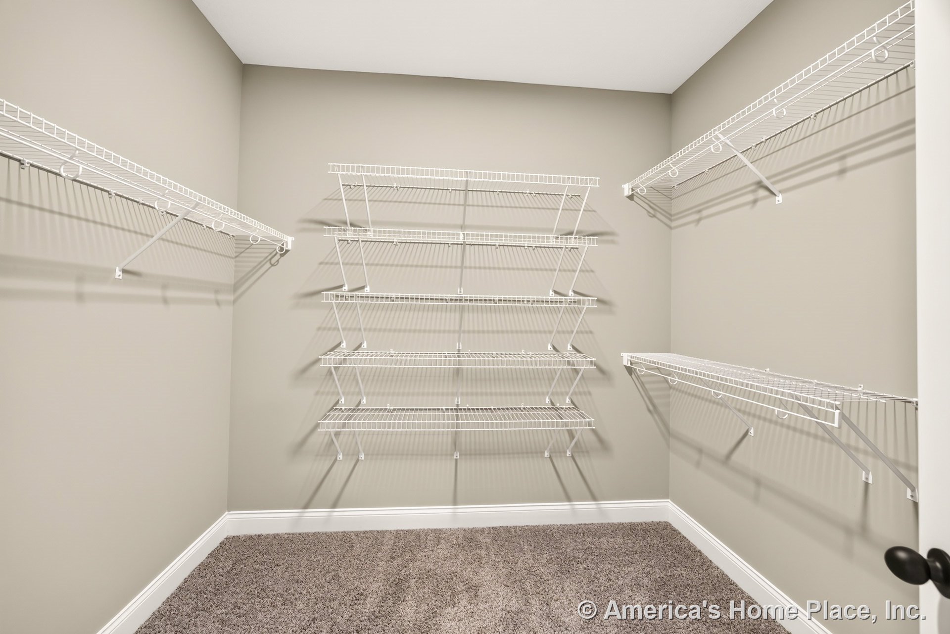 Walk-in closet with multiple white wire shelving units, beige painted walls, carpet flooring, white baseboard trim, and recessed ceiling lighting.