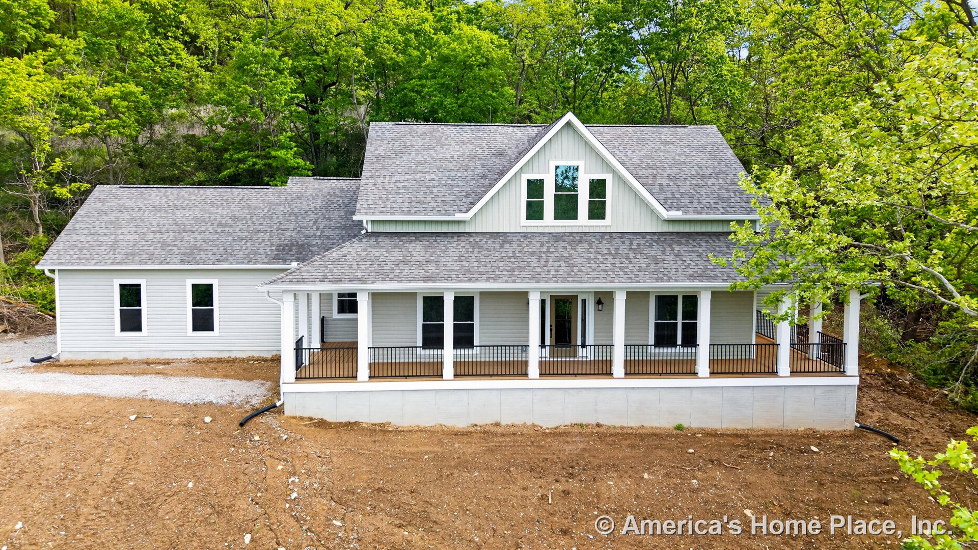 Large covered front porch with white columns and black metal railings, gray shingle gabled roof, white siding exterior, multiple double-hung windows, concrete foundation, entry