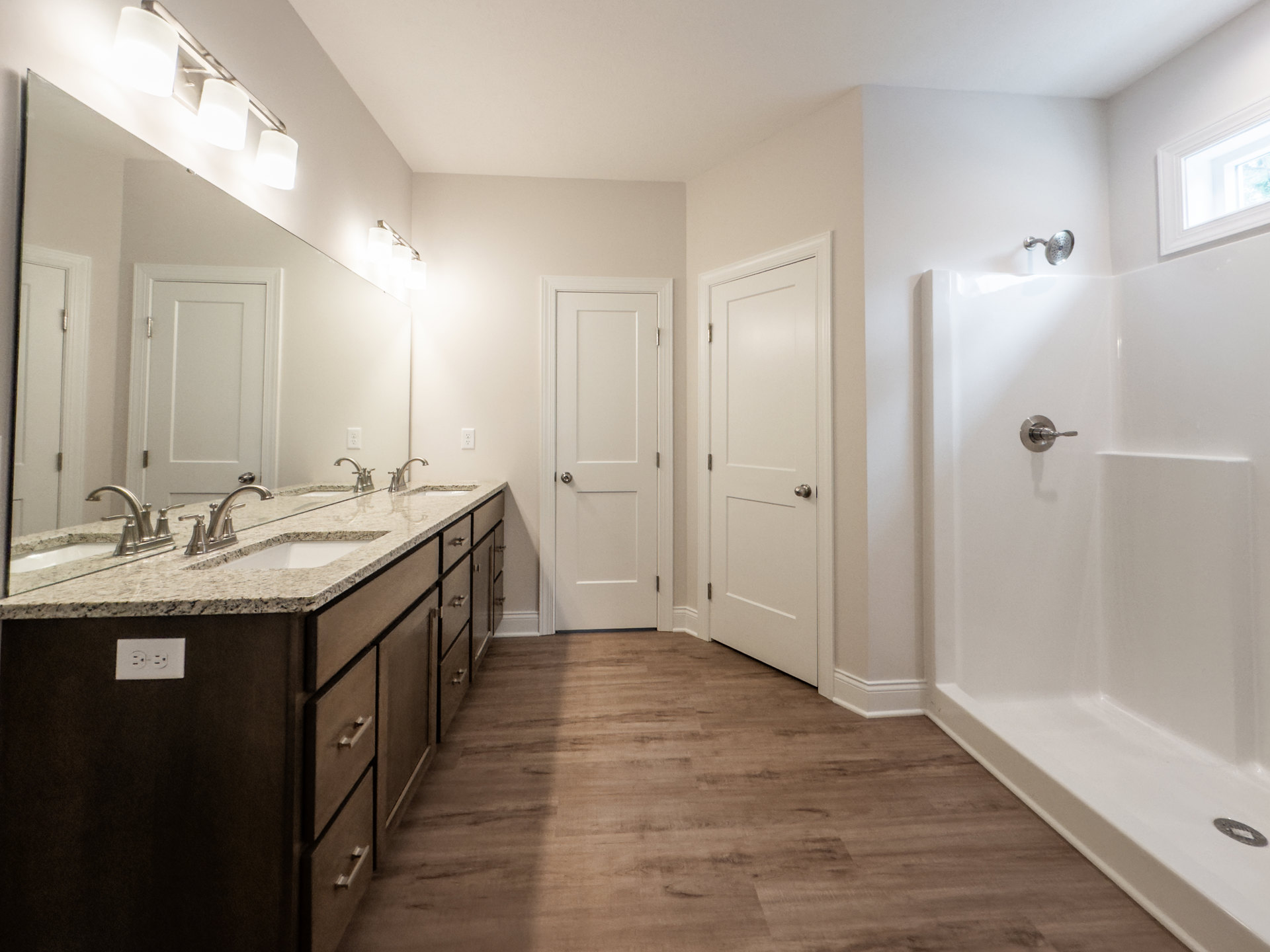 Modern bathroom featuring a tiled shower with chrome showerhead, white vanity with undermount sink and silver faucet, white door with brushed nickel handle, recessed lighting, and