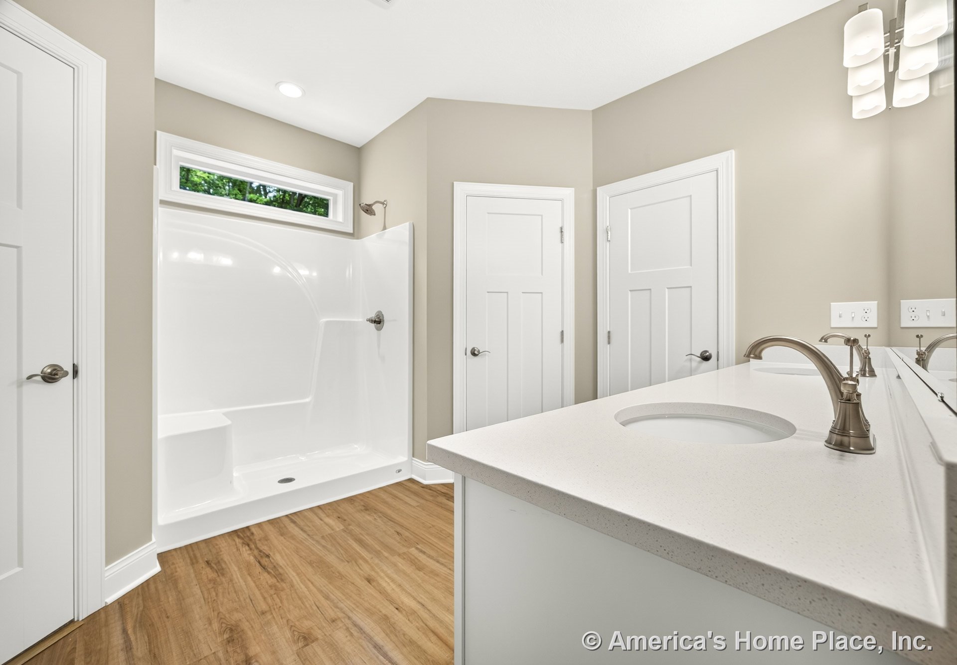 Walk-in shower with built-in seat and rectangular window above, quartz countertop vanity with wall-mounted lighting and mirror, wood-look flooring, white paneled doors, neutral