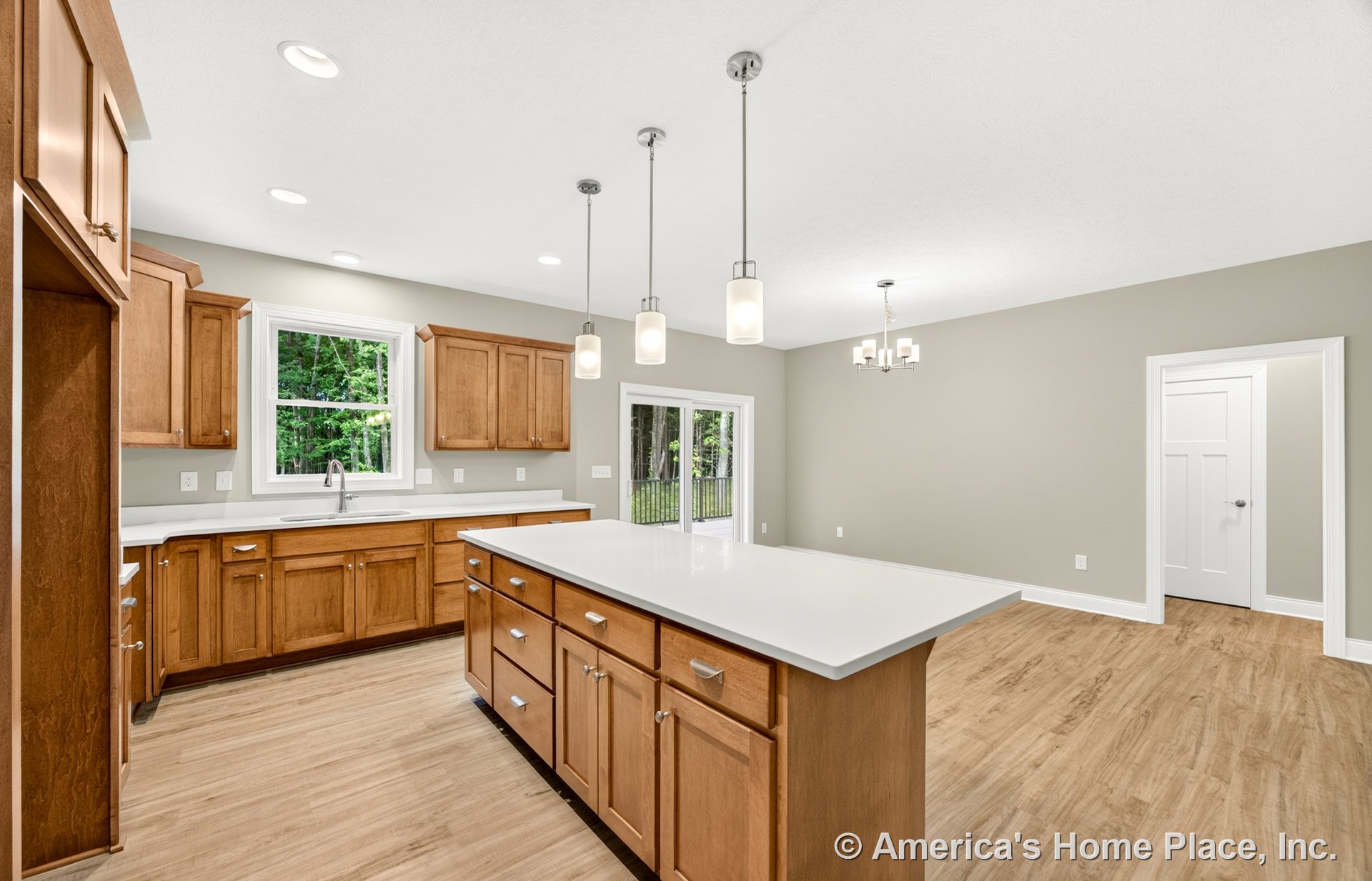 Natural wood kitchen cabinets, large central island with white quartz countertops, pendant lights above island, double window over sink, sliding glass door leading to porch, light