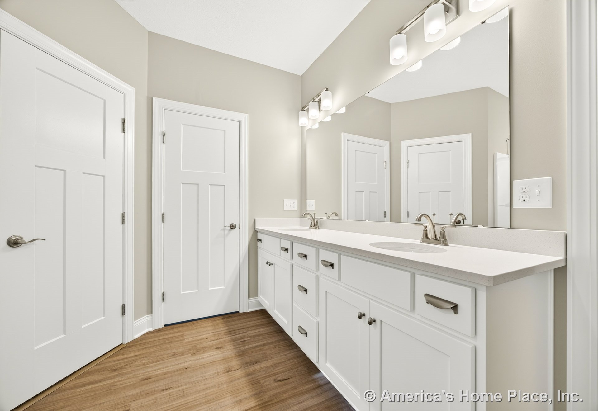 Double sink vanity with white shaker cabinets and quartz countertop, large wall mirror, modern brushed nickel vanity lighting, wood-look flooring, neutral wall color, and panel