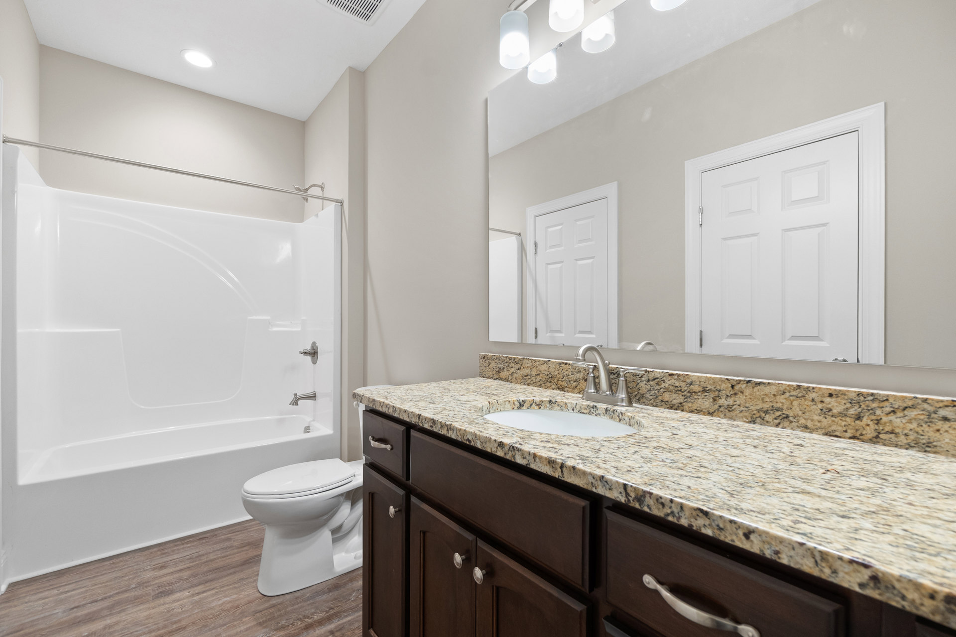 Bathroom with white tile floor, white toilet, rectangular sink set in a light countertop, glass-enclosed shower, white paneled door, and modern chrome fixtures.