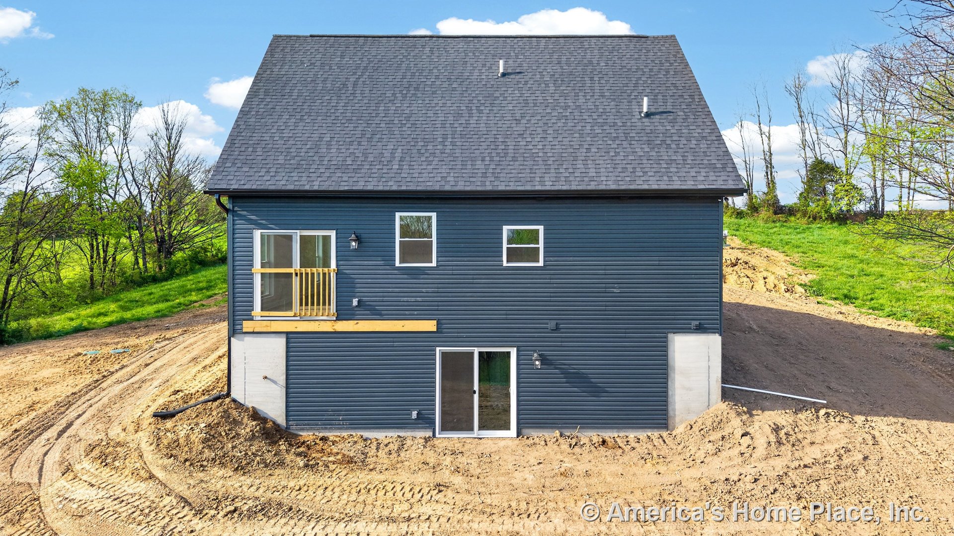 Blue horizontal siding and asphalt shingle roof with multiple sliding glass doors, rectangular windows, small balcony featuring wood railing, exterior wall-mounted lighting, and